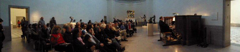 Panorama of man playing organ with audience